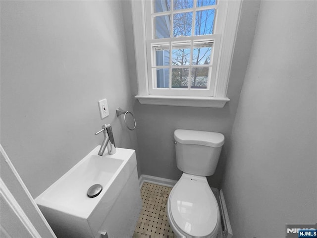 bathroom with toilet, baseboards, and a sink