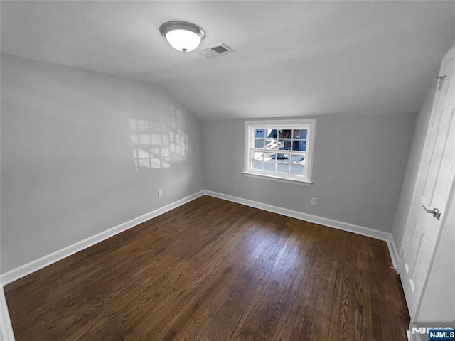 interior space with dark wood finished floors, visible vents, baseboards, and vaulted ceiling