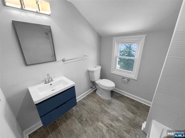 bathroom featuring vanity, toilet, wood finished floors, and baseboards