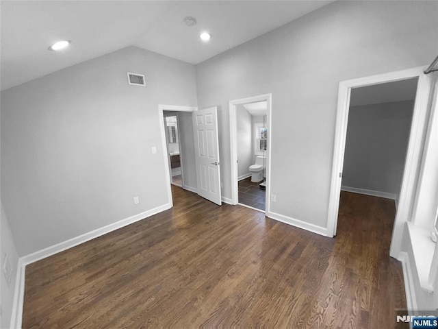 unfurnished bedroom featuring visible vents, dark wood-style flooring, baseboards, and vaulted ceiling