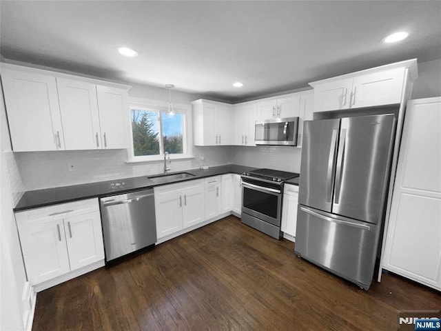 kitchen featuring dark wood finished floors, appliances with stainless steel finishes, dark countertops, and a sink