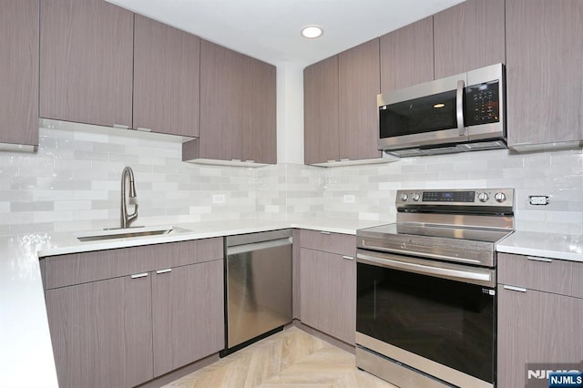 kitchen with a sink, backsplash, recessed lighting, appliances with stainless steel finishes, and light countertops