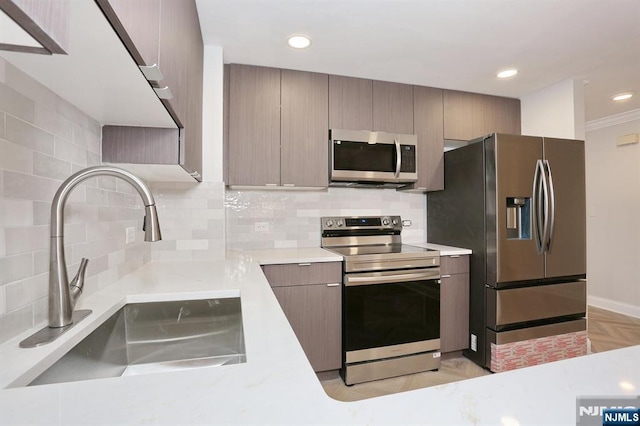 kitchen with tasteful backsplash, light countertops, appliances with stainless steel finishes, modern cabinets, and a sink