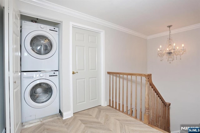 laundry room with stacked washer and clothes dryer, ornamental molding, laundry area, and an inviting chandelier