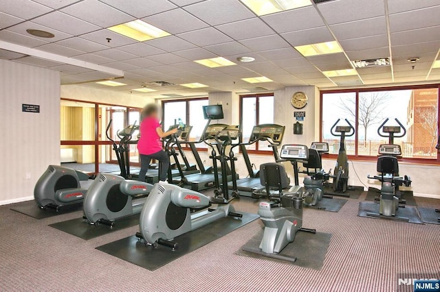 exercise room with a drop ceiling, baseboards, and visible vents