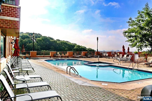 community pool featuring a community hot tub, a patio, and fence