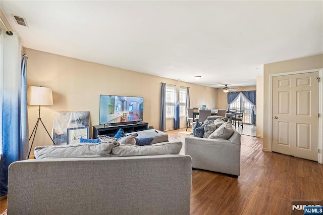 living room with visible vents, wood finished floors, and a ceiling fan