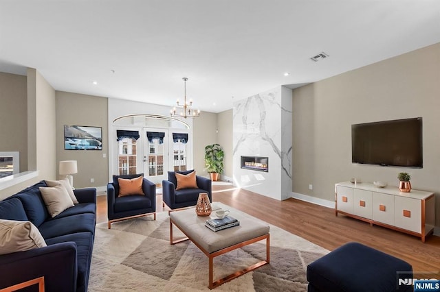 living room featuring light wood-type flooring, visible vents, recessed lighting, a fireplace, and a chandelier