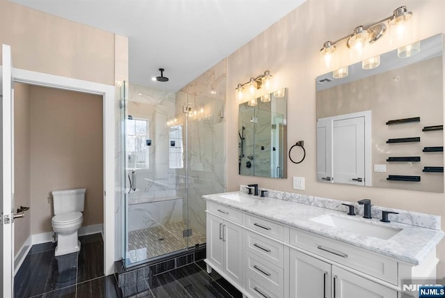 full bathroom with double vanity, toilet, a marble finish shower, and a sink