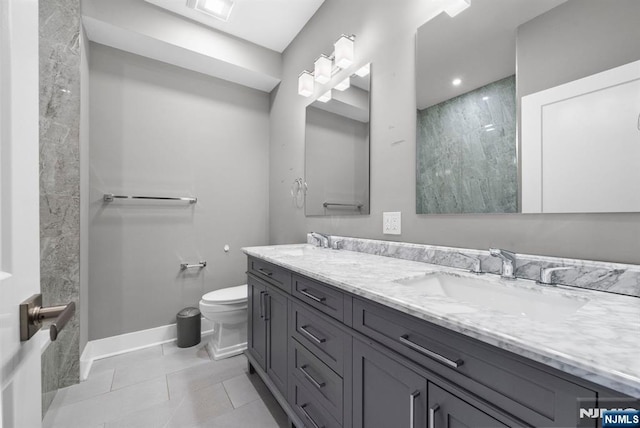 bathroom featuring tile patterned flooring, double vanity, toilet, and a sink