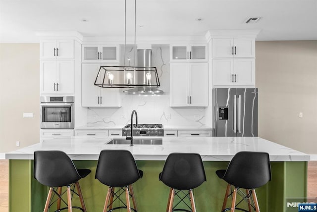 kitchen with visible vents, a center island with sink, extractor fan, appliances with stainless steel finishes, and tasteful backsplash