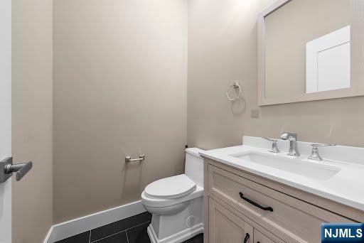 bathroom featuring baseboards, toilet, vanity, and tile patterned flooring