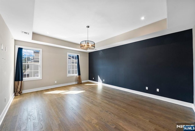 spare room featuring an inviting chandelier, wood finished floors, baseboards, and a wealth of natural light