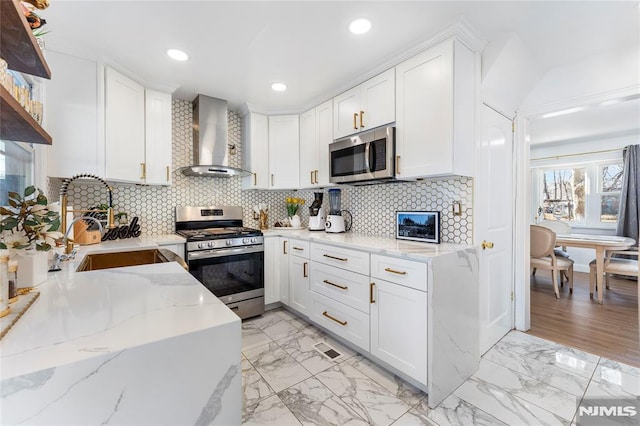 kitchen featuring a sink, marble finish floor, appliances with stainless steel finishes, and wall chimney exhaust hood