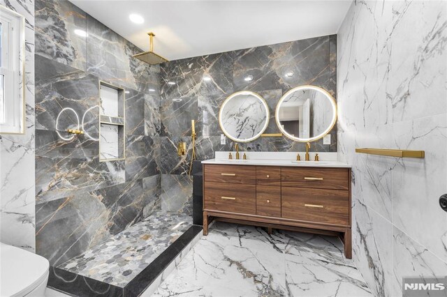 full bath featuring a marble finish shower, double vanity, marble finish floor, stone wall, and a sink