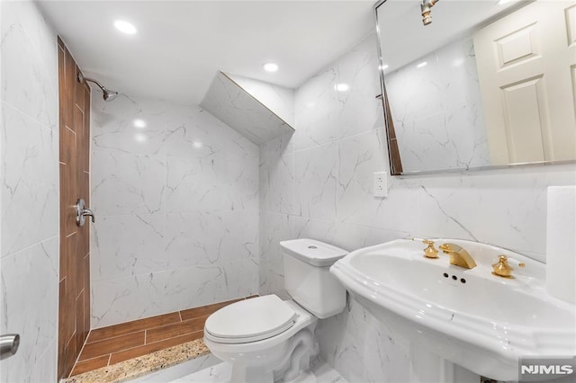 bathroom featuring toilet, recessed lighting, wood finished floors, tile walls, and a sink