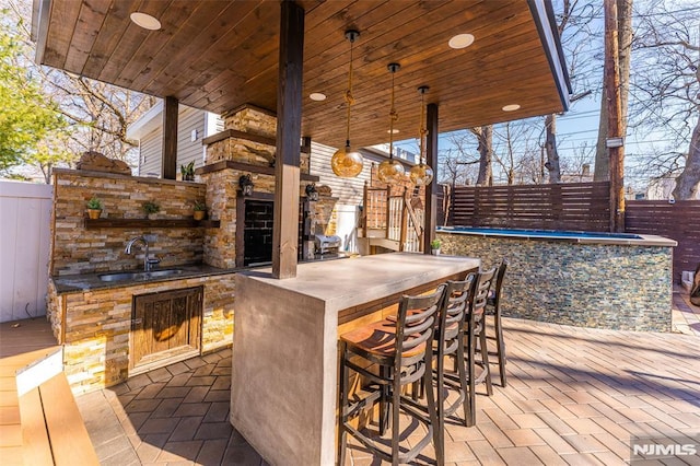 view of patio with a sink, outdoor wet bar, and fence