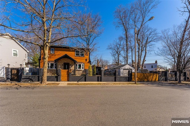 view of front of home with a fenced front yard, stone siding, a residential view, and a gate