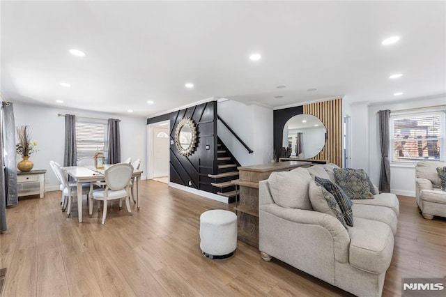 living area with stairway, arched walkways, light wood-type flooring, and a wealth of natural light