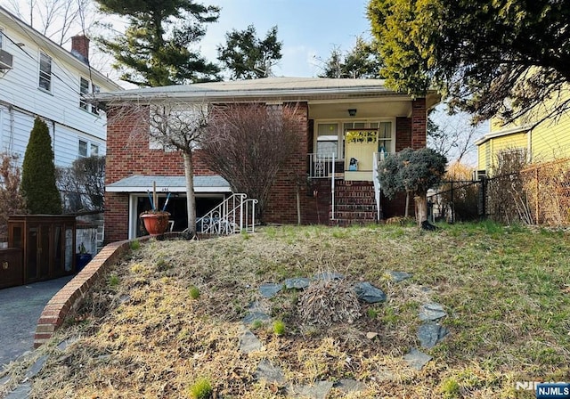 view of front facade with brick siding, covered porch, and fence