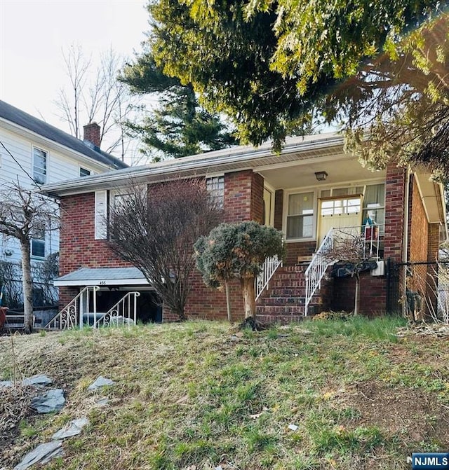 rear view of house with a porch and brick siding