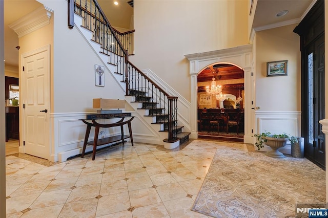 entryway with a chandelier, stairway, arched walkways, and crown molding