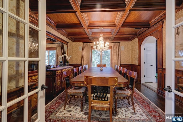 dining room featuring a wainscoted wall, coffered ceiling, wood finished floors, arched walkways, and wooden ceiling