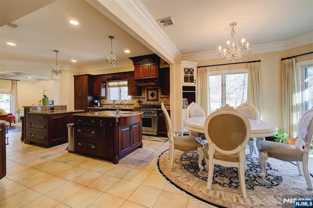 kitchen featuring a center island with sink, plenty of natural light, an inviting chandelier, and stainless steel stove