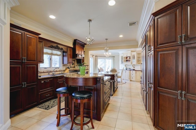 kitchen featuring ornamental molding, visible vents, light tile patterned floors, and a center island