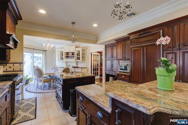 kitchen with visible vents, high quality appliances, a kitchen island, an inviting chandelier, and light tile patterned flooring