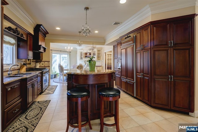 kitchen featuring visible vents, a center island, stainless steel range with gas cooktop, a notable chandelier, and a sink