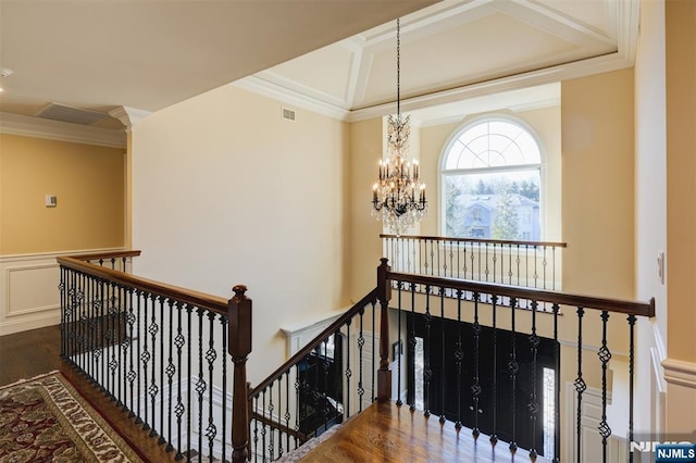 stairs with visible vents, coffered ceiling, wood finished floors, crown molding, and a chandelier