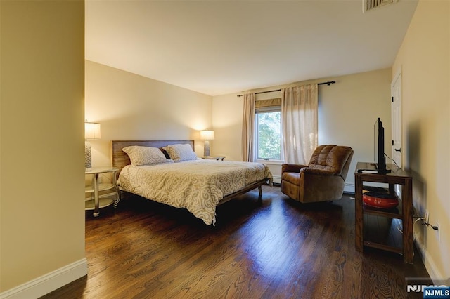 bedroom with wood finished floors, visible vents, baseboard heating, and baseboards