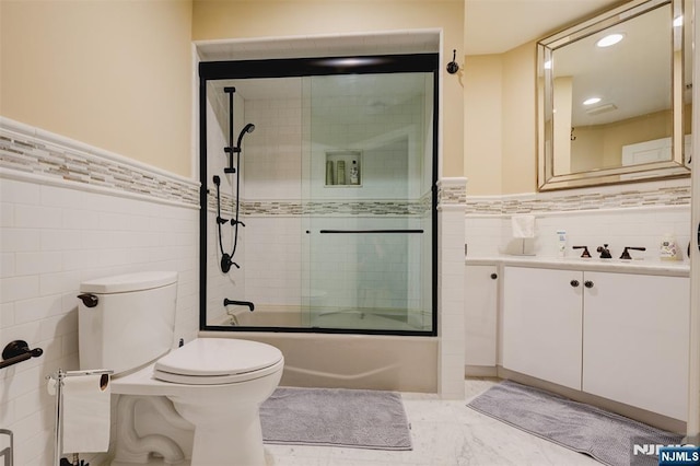 bathroom with toilet, tile walls, and wainscoting