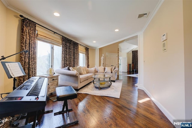 living area featuring visible vents, crown molding, baseboards, and wood finished floors