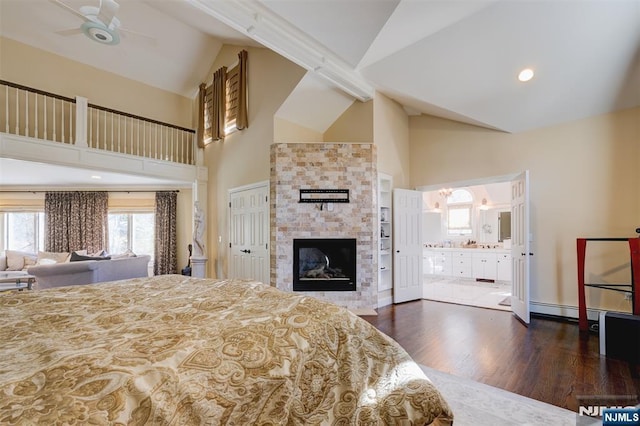 bedroom featuring ensuite bath, a fireplace, high vaulted ceiling, and wood finished floors