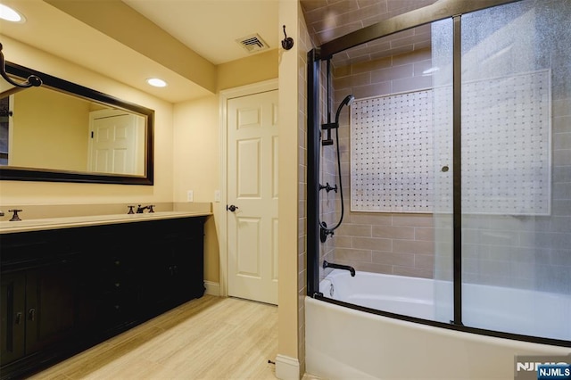 bathroom featuring visible vents, recessed lighting, wood finished floors, enclosed tub / shower combo, and vanity