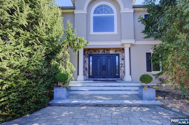 view of exterior entry featuring stone siding and stucco siding