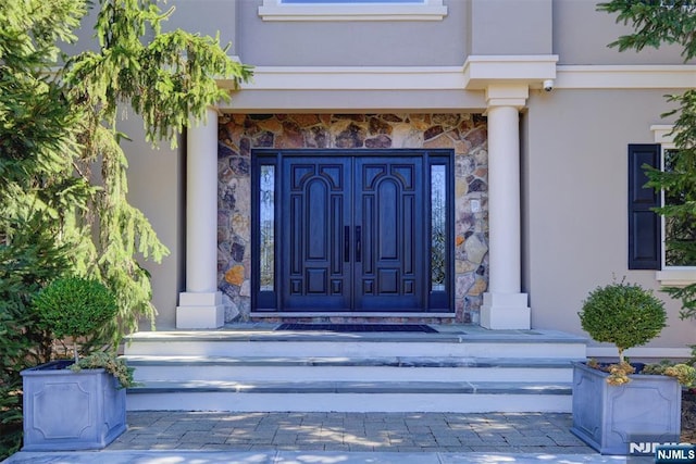 property entrance featuring stucco siding and stone siding