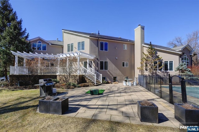 rear view of house with a patio, a yard, a pergola, a chimney, and stucco siding