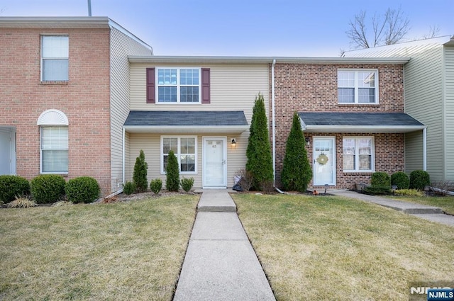 view of property with a front yard and brick siding