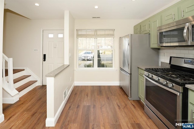 kitchen featuring visible vents, dark wood-style floors, stainless steel appliances, green cabinetry, and decorative backsplash