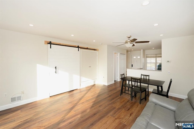 living room with wood finished floors, a ceiling fan, visible vents, recessed lighting, and a barn door