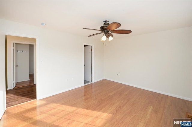 spare room with a ceiling fan, light wood-type flooring, and baseboards