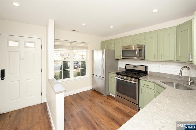 kitchen featuring tasteful backsplash, a sink, stainless steel appliances, and green cabinetry