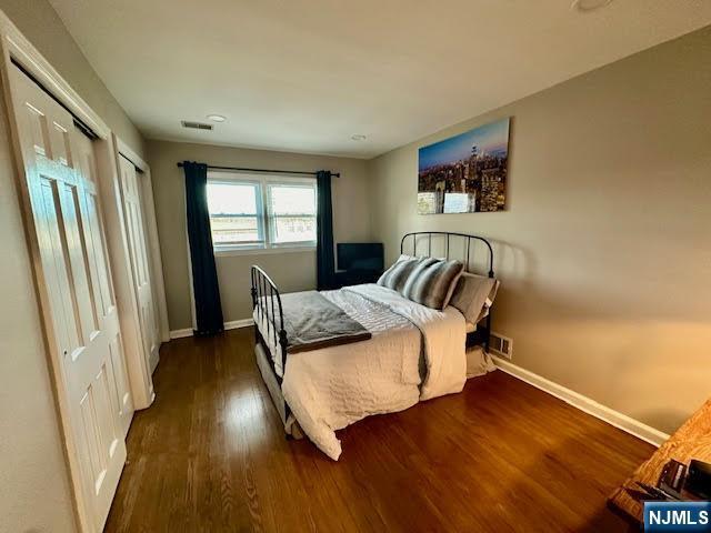 bedroom with visible vents, baseboards, and wood finished floors