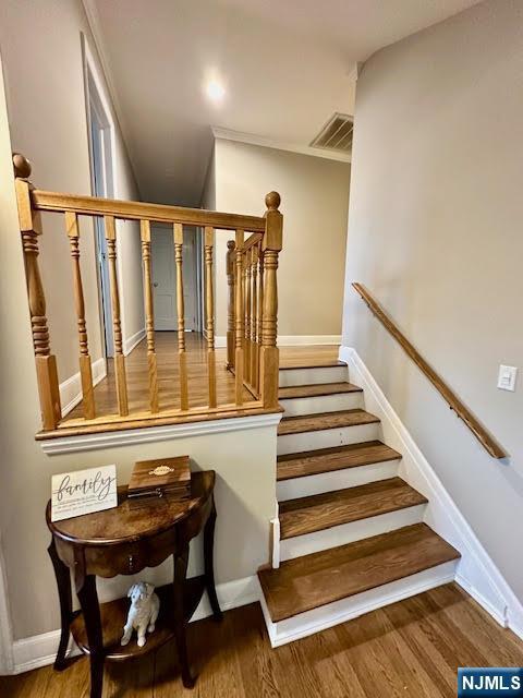 staircase featuring visible vents, baseboards, and wood finished floors