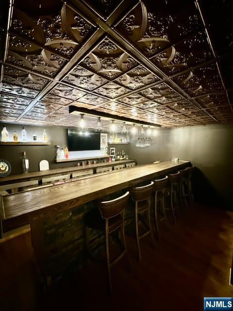 bar with an ornate ceiling, a bar, and wood finished floors