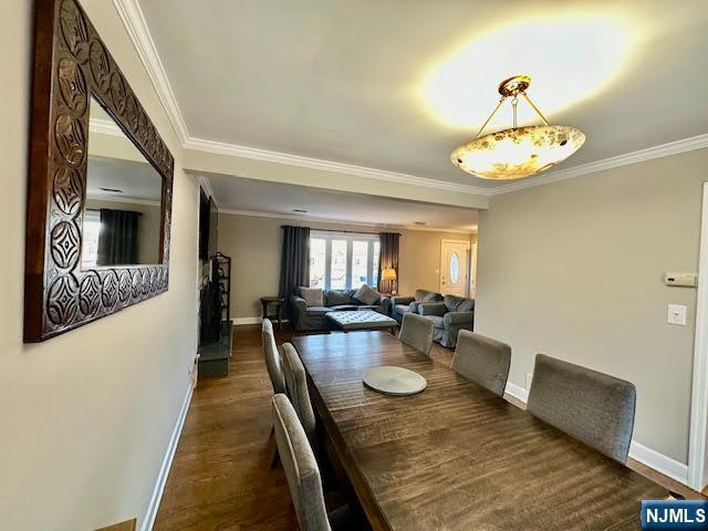 dining space featuring crown molding, baseboards, and dark wood-style flooring