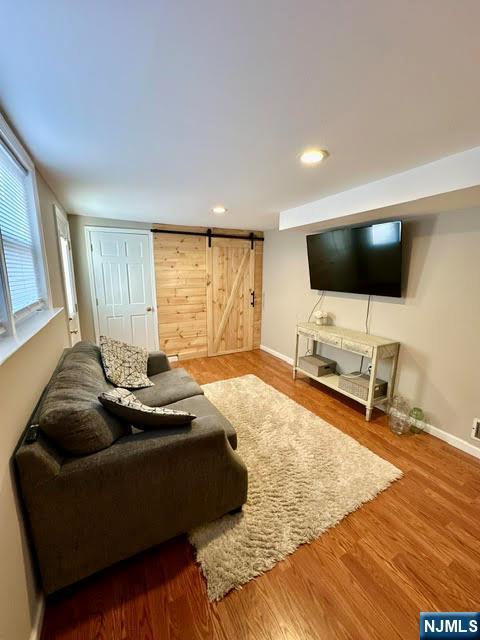 living area with recessed lighting, a barn door, baseboards, and wood finished floors